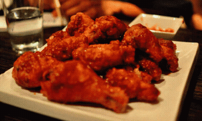A White Plate Topped With Fried Chicken And A Glass Of Water In The Background GIF