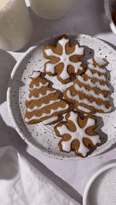 A White Plate Topped With Gingerbread Cookies In The Shapes Of A Tree Snowflake And Snowflake GIF