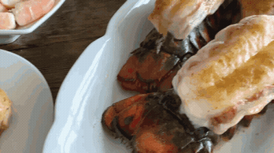 A White Plate Topped With Lobster Tails On A Table GIF