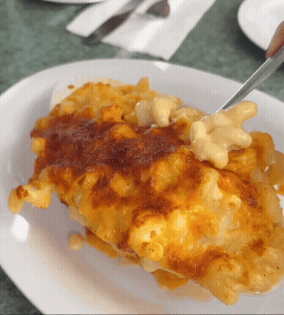 A White Plate Topped With Macaroni And Cheese And A Fork GIF