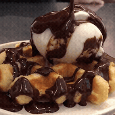 A White Plate Topped With Waffles And Ice Cream With Chocolate Sauce GIF
