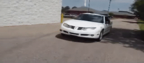 A White Pontiac Car Is Driving Down A Road GIF