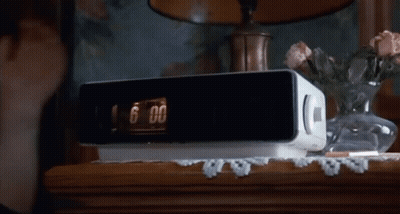 A White Radio Is Sitting On A Wooden Table Next To A Vase Of Flowers GIF