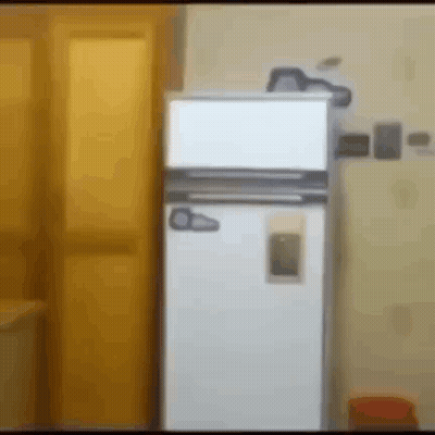 A White Refrigerator Is Sitting In A Room Next To A Yellow Door GIF