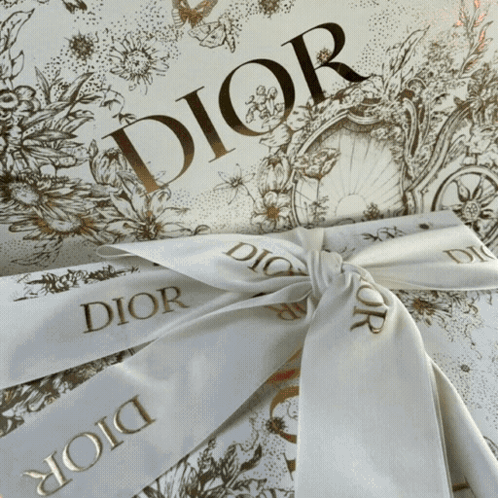A White Ribbon With Dior Written On It Is Tied In A Bow GIF