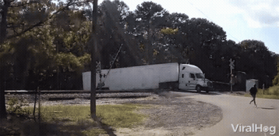 A White Semi Truck Is Crossing A Railroad Crossing With A Viralhog Logo In The Background GIF