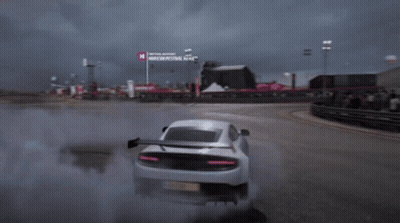 A White Sports Car Is Drifting On A Race Track With A Sign That Says Moscow Festival Next To It GIF