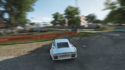 A White Sports Car Is Driving Down A Dirt Road With A Fence Behind It GIF