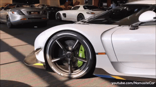 A White Sports Car With A Michelin Tire Is Parked In A Parking Lot GIF