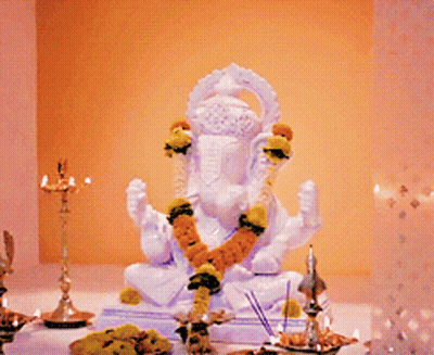 A White Statue Of A Deity With A Garland Around His Neck GIF