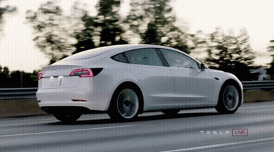 A White Tesla Is Driving Down A Highway GIF