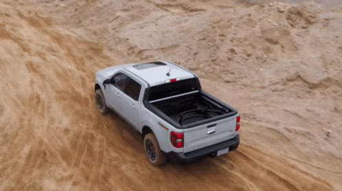A White Truck Is Driving Through A Dirt Field GIF