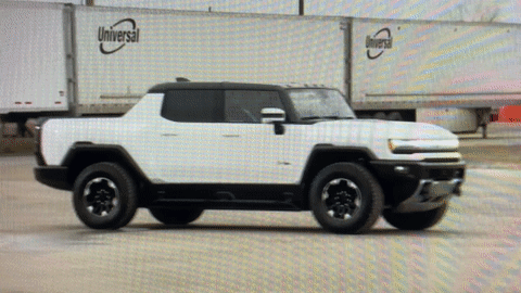 A White Truck Is Parked In Front Of A Truck With The Word Universal On It GIF