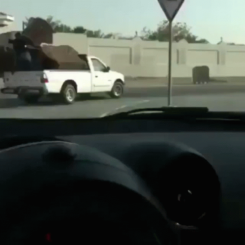 A White Truck Is Parked On The Side Of The Road Next To A Triangle Sign GIF