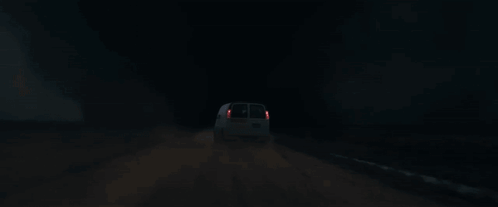 A White Van Is Driving Down A Road At Night With A Tornado In The Background GIF