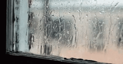 A Window With Rain Drops On It And A Person Looking Out . GIF