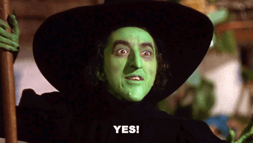 A Witch With Green Face Paint And A Black Hat Says " Yes " GIF