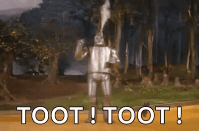 A Wizard Of Oz Character Is Standing In The Woods With The Words Toot ! Toot ! Above Him . GIF