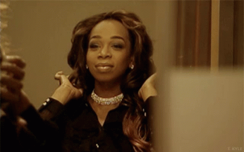 A Woman Adjusts Her Hair In Front Of A Mirror With The Name T. Kyle On The Bottom Right GIF