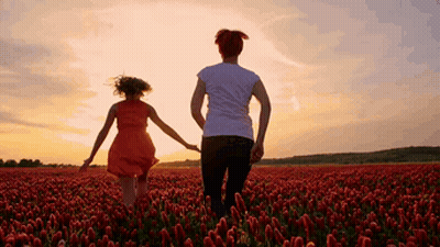 A Woman And A Girl Are Holding Hands In A Field Of Red Flowers GIF
