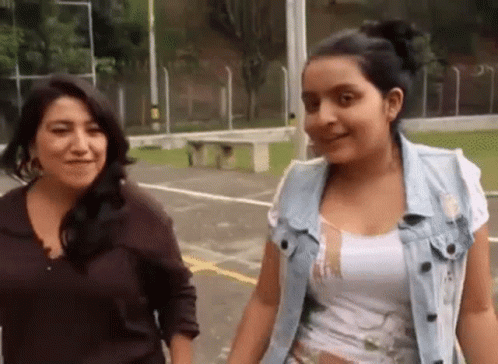 A Woman And A Girl Are Standing Next To Each Other In A Park . GIF