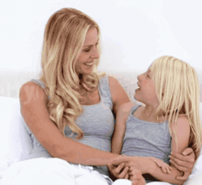 A Woman And A Little Girl Are Sitting On A Bed GIF