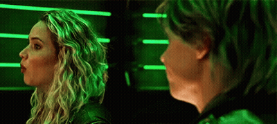 A Woman And A Man Are Standing Next To Each Other In Front Of A Green Light . GIF
