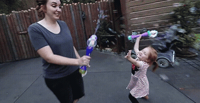 A Woman And Child Are Playing With Soap Bubbles GIF