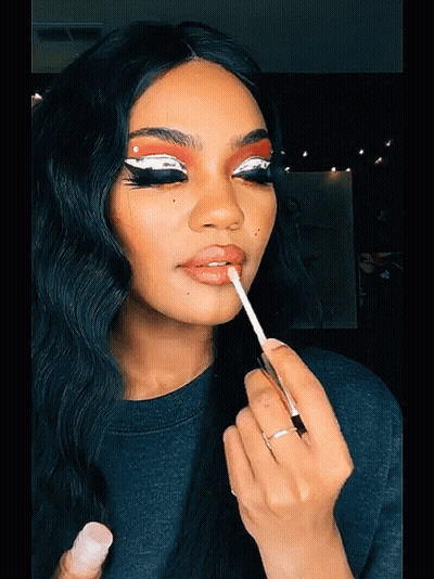 A Woman Applies Lip Gloss To Her Lips With A Brush GIF