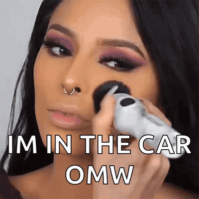 A Woman Applying Makeup With The Words Im In The Car Omw GIF