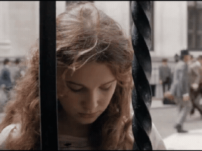 A Woman Behind Bars With Her Eyes Closed Looks Down GIF