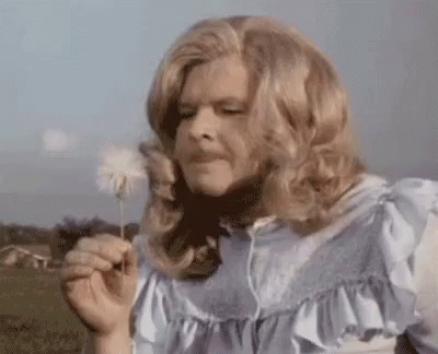 A Woman Blowing A Dandelion In A Field . GIF