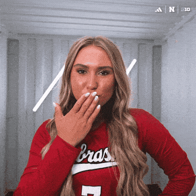 A Woman Blowing A Kiss Wearing A Braos Shirt GIF