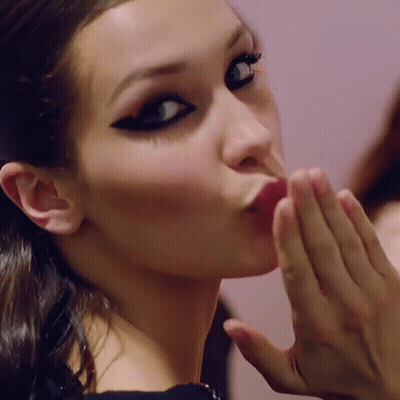 A Woman Blowing A Kiss With Her Hand GIF