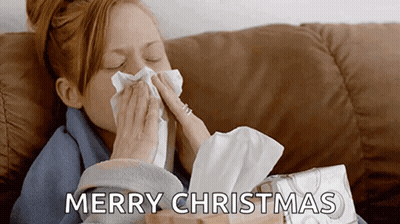 A Woman Blowing Her Nose While Sitting On A Couch With A Box Of Tissues In Front Of Her . GIF