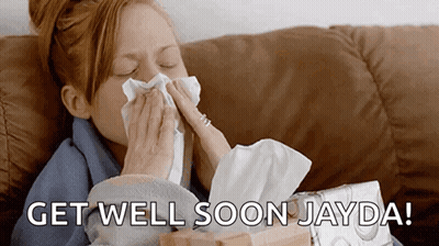 A Woman Blowing Her Nose While Sitting On A Couch With The Words Get Well Soon Jayda Written On The Bottom GIF