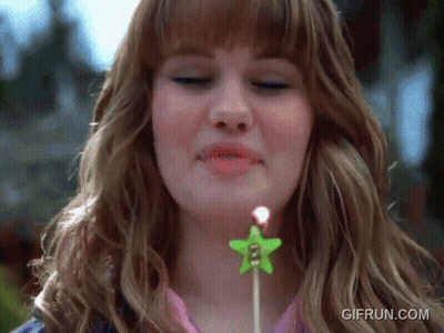 A Woman Blowing Out A Candle With A Star On It GIF
