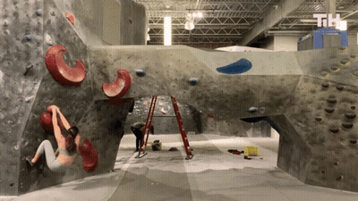 A Woman Climbs A Rock Wall With The Letters Th On The Bottom Left GIF