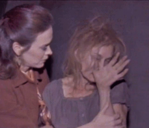 A Woman Covering Another Woman 'S Face With Her Hands GIF