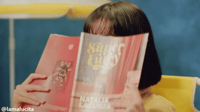 A Woman Covering Her Face With A Magazine Titled Super Lucky GIF