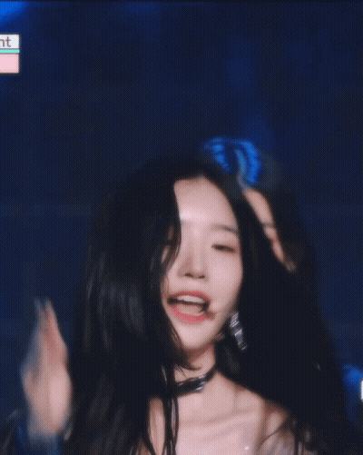 A Woman Covering Her Face With Her Hand And Smiling In Front Of A Blue Background GIF
