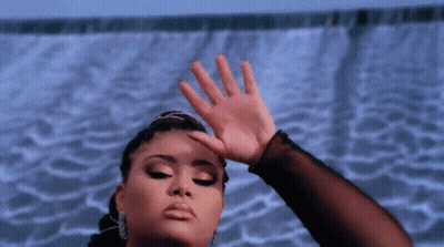 A Woman Covering Her Face With Her Hand In Front Of A Blue Background GIF