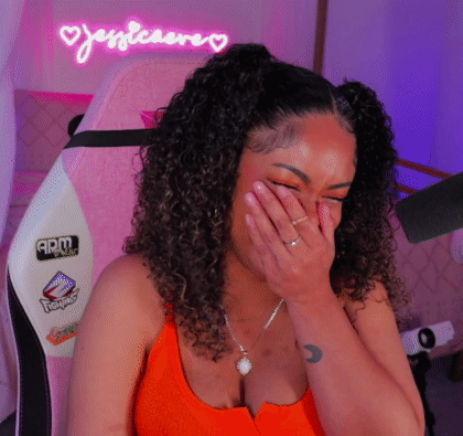 A Woman Covering Her Face With Her Hand In Front Of A Neon Sign That Says Justiceare GIF