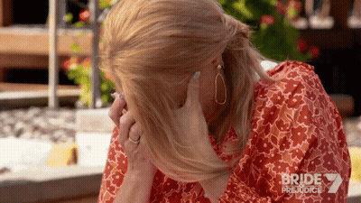 A Woman Covering Her Face With Her Hand While Wearing A Red Dress With Bride Prejudice Written On The Bottom GIF