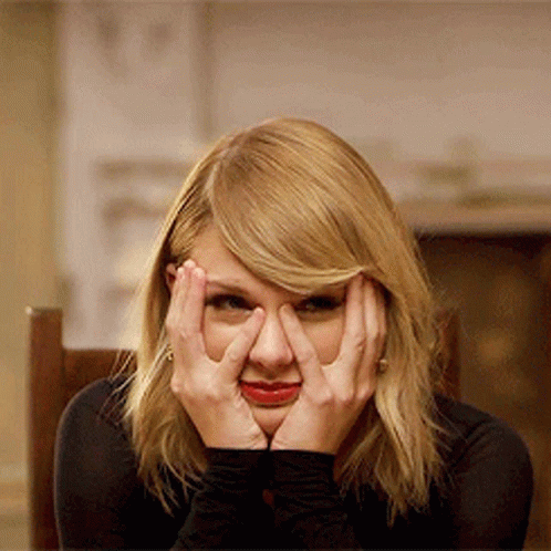 A Woman Covering Her Face With Her Hands And Looking At The Camera GIF