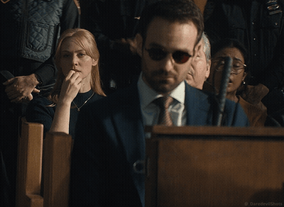 A Woman Covering Her Mouth While A Man In A Suit And Tie Looks On GIF