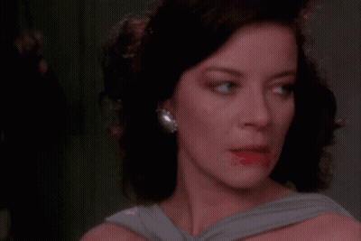 A Woman Covering Her Mouth With Her Hand While Looking At The Camera GIF
