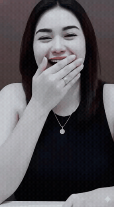 A Woman Covering Her Mouth With Her Hand While Wearing A Necklace And A Ring GIF