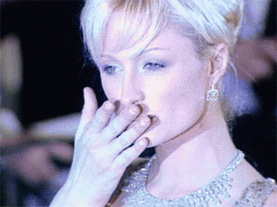 A Woman Covering Her Mouth With Her Hand While Wearing Earrings GIF
