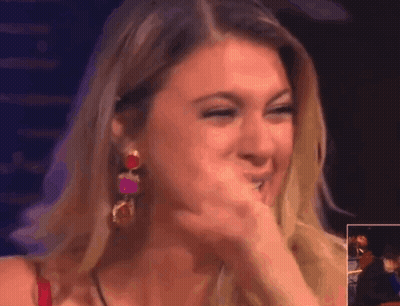 A Woman Covering Her Mouth With Her Hand While Wearing Earrings GIF